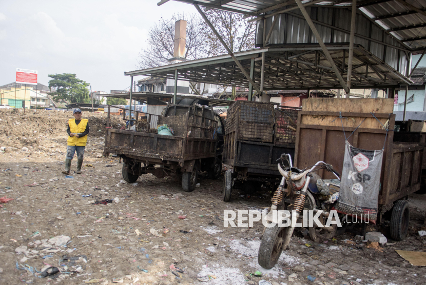 Petugas berjalan di dekat kendaraan pengangkut sampah yang terparkir di Tempat Pembuangan Sementara (TPS) Pasar Caringin, Bandung, Jawa Barat, Selasa (11/2/2025). Tim Penegakan Hukum Kementerian Lingkungan Hidup (KLH) menyegel dan menutup TPS tersebut akibat melakukan pelanggaran lingkungan terkait pengelolaan dalam menimbun sampah dan membakar sampah memakai insenerator tanpa izin. 