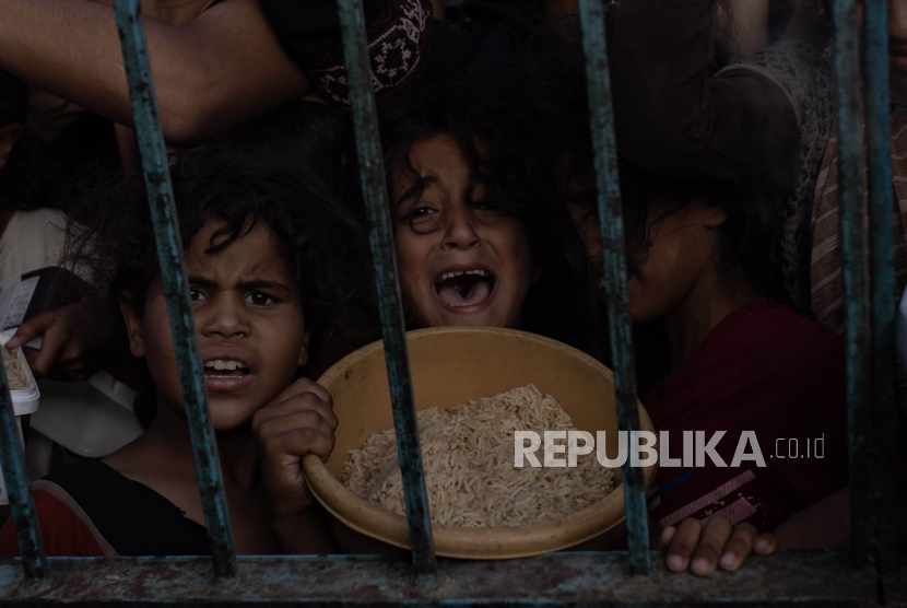 Anak-anak berkumpul untuk mendapatkan makanan dari komunitas amal di Khan Younis, Gaza, pada Juni 2024. Masyarakat diminta menyadari kekejaman yang menimpa masyarakat di Gaza, Palestina. (