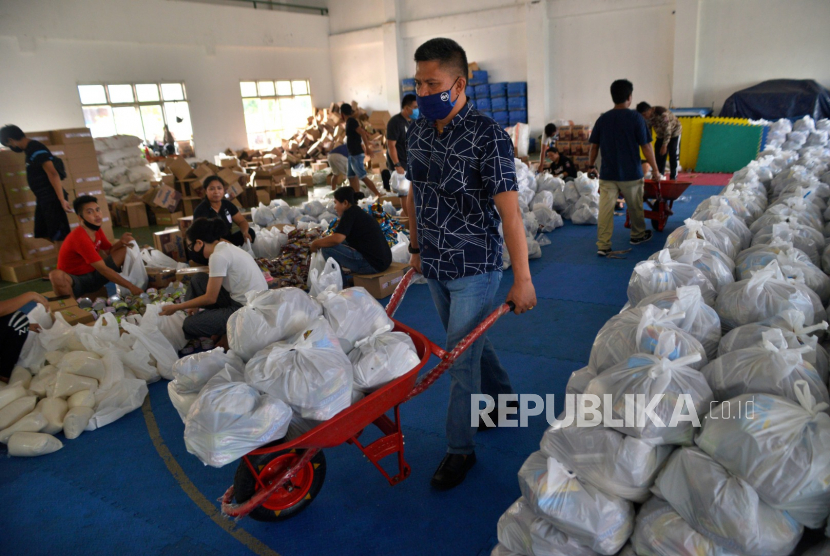 Relawan Dinas Sosial dan Pemberdayaan Masyarakat Kota Manado memindahkan paket-paket bantuan yang akan didistribusikan dari gelanggang olahraga Youth Center Manado, Sulawesi Utara, Kamis (30/4/2020). Sebanyak 66