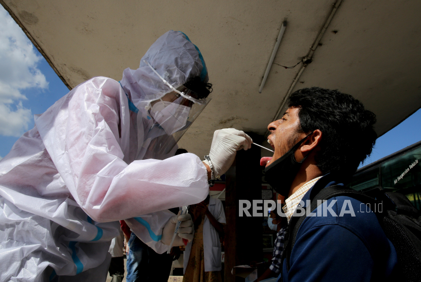  Seorang petugas kesehatan mengambil sampel usap dari seseorang untuk tes COVID-19 di halte bus kota di Bangalore, India, 20 November 2020. India menemukan enam kasus infeksi jenis baru virus corona baru yang lebih menular. 