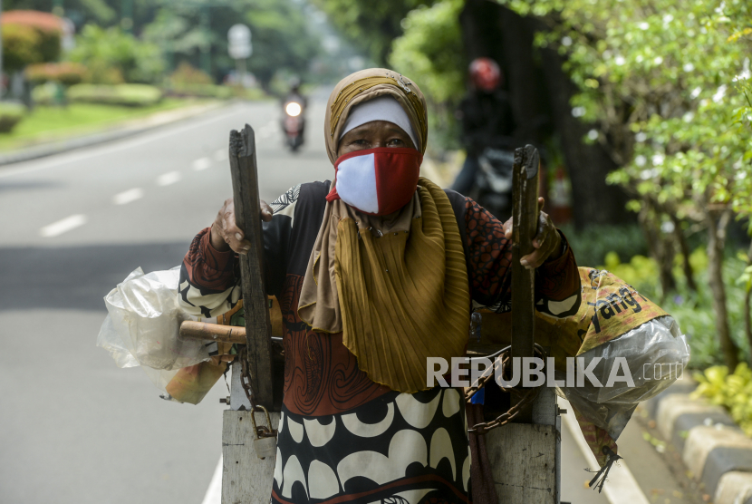 Seorang pemulung mendorong gerobaknya dengan memakai masker untuk mengantisipasi virus Corona di Jalan Imam Bonjol, Menteng, Jakarta, Senin (13/4). Republika/Putra M