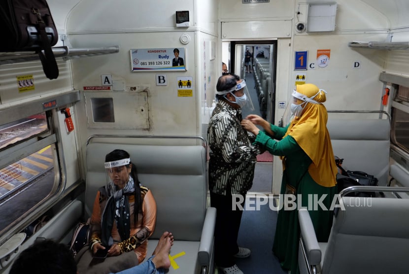 Penumpang memakai masker dan pelindung wajah (Face Shield) di Kereta Api (KA) Ranggajati relasi Cirebon-Jember saat transit di Stasiun Balapan, Solo, Jawa Tengah, Ahad (14/6/2020). PT KAI Daerah Operasi (Daops) VI Yogyakarta menerapkan protokol kesehatan pencegahan penyebaran COVID-19 bagi penumpang, dengan mengenakan masker dan pelindung wajah, memakai baju lengan panjang atau jaket, serta menunjukkan surat bebas COVID-19 perjalanan KA, selama masa adaptasi kebiasaan baru