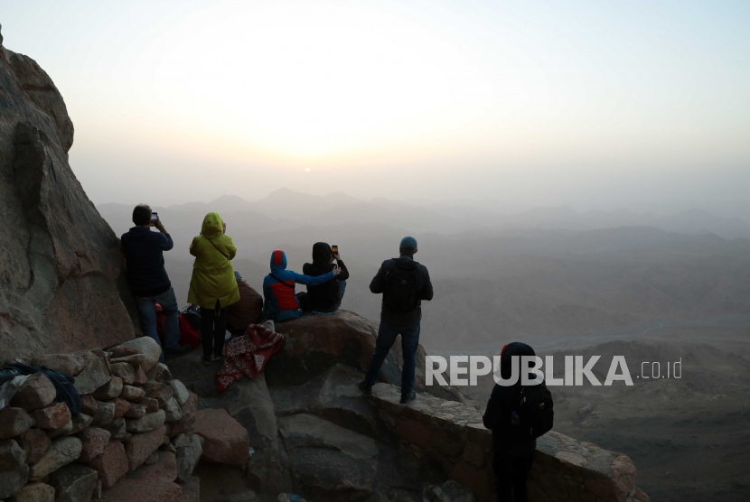  Wisatawan menyaksikan matahari terbit di luar gereja di puncak Gunung Moses, kota Saint Catherine, Sinai Selatan, Mesir, 20 Maret 2021 (dikeluarkan 22 Maret 2021).