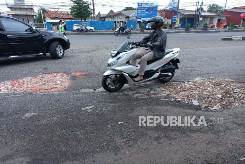 Pengendara menghindari jalanan yang berlubang di Jl Sudirman, Kranji, Gg Banteng Kota Bekasi tepatnya Fly Over Kranji. Jalanan ini sudah satu tahu rusak parah belum diperbaiki. Ahad (19/2/2023).