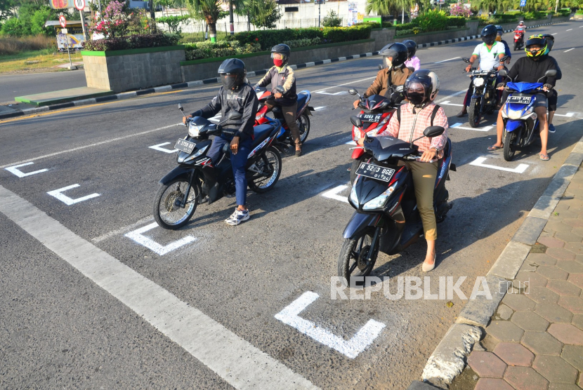Pengendara sepeda motor berhenti di belakang garis untuk menjaga jarak antarpengendara di jalan jalur pantura di Kudus, Jawa Tengah, Kamis (23/7/2020). Garis pembatas tersebut untuk membatasi jarak antarpengendara di tempat lampu lalu lintas guna mencegah kerumunan yang dapat menjadi medium penyebaran COVID-19. 