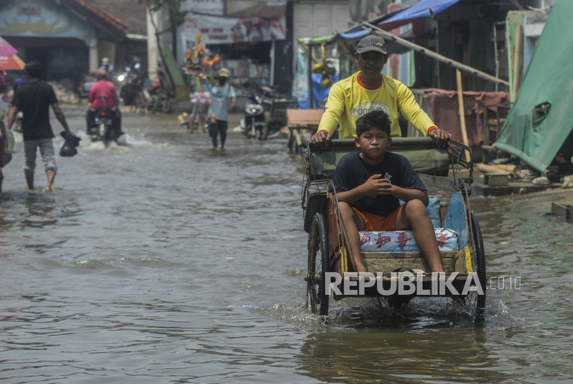 Warga menaiki becak saat terjadi banjir rob di kawasan Muara Angke, Jakarta Utara, Rabu (5/1/2022).