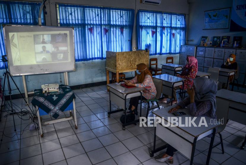 Sejumlah orang tua murid mengikuti simulasi sekolah hybrid di SMP 255, Duren Sawit, Jakarta, Selasa (30/3). Kegiatan tersebut dilakukan untuk mengenalkan orang tua murid mengenai tata cara sekolah tatap muka dan daring yang rencananya akan dilakukan ketika memasuki tahun ajaran baru pada Juli 2021. Republika/Putra M. Akbar
