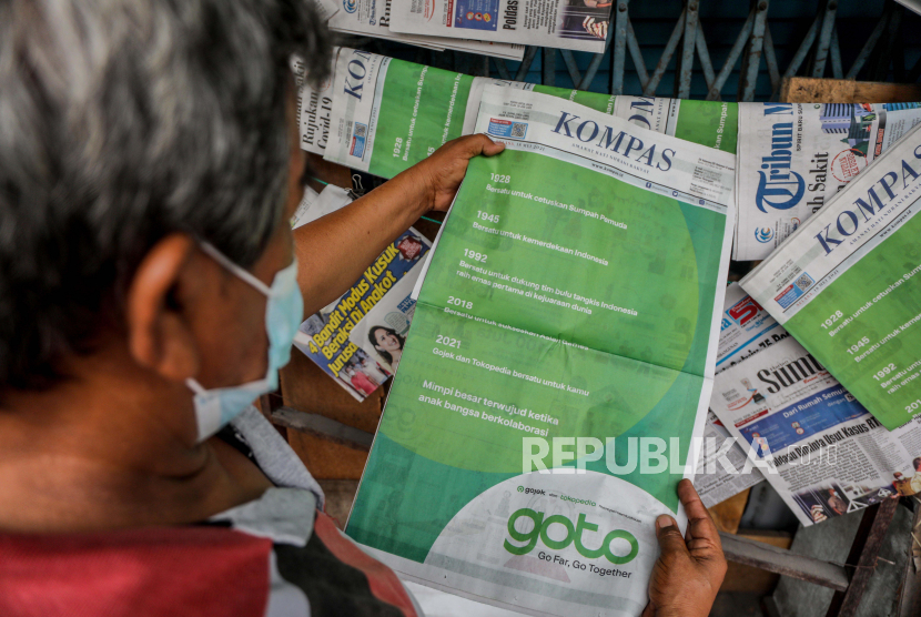 Seorang pria melihat iklan di surat kabar yang menunjukkan merger antara Gojek dan Tokopedia di Medan, Sumatera Utara, Selasa (18/5). Perusahaan ride hailing Gojek dan perusahaan e-commerce Tokopedia telah mengumumkan merger dan membentuk perusahaan bernilai miliaran dolar. GoTo Group.