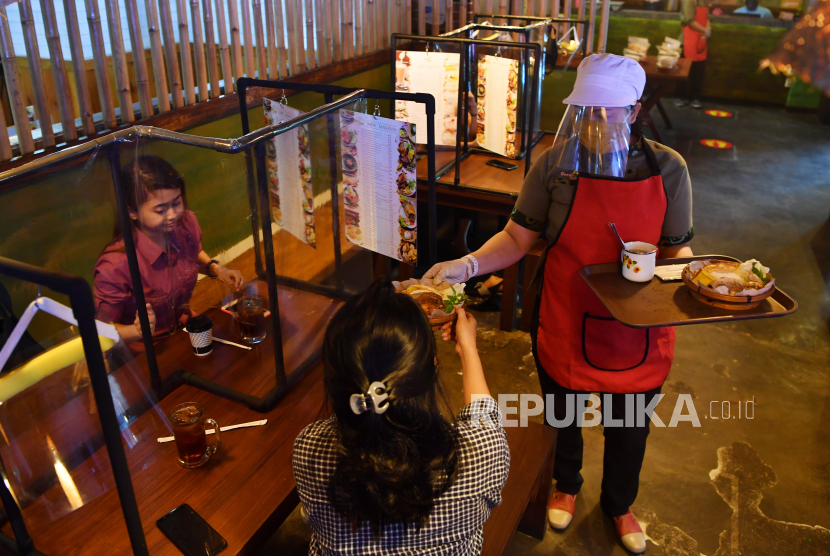 Karyawan mengantar makanan pesanan pelanggannya di salah satu restoran di Plaza Marina, Surabaya, Jawa Timur, Selasa (16/6/2020). Sejumlah restoran dan rumah makan di Surabaya mulai membuka layanan makan di tempat dengan protokol kesehatan ketat setelah penerapan Pembatasan Sosial Berskala Besar (PSBB) di wilayah itu memasuki masa transisi  menuju era normal baru