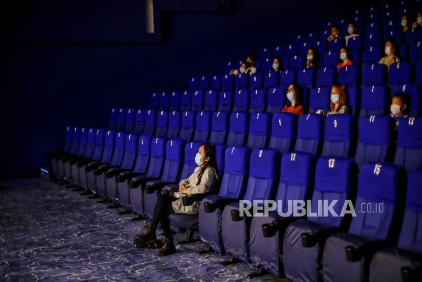 Orang-orang memakai topeng pelindung wajah dan mengamati jarak sosial ketika menonton film di sebuah bioskop di Shanghai, Cina, 20 Juli 2020. Pembukaan kembali bioskop di DKI Jakarta merujuk dari praktik protokol kesehatan bioskop di luar negeri.