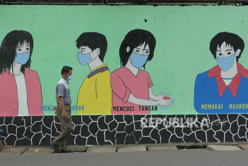 Warga melintasi area mural berisi imbauan penerapan protokol kesehatan di kawasan Halim Perdanakusuma, Jakarta, Rabu (16/6). Mural tersebut menghiasi sepanjang kurang lebih 50 meter dalam rangka menyemarakkan HUT ke-494 Kota Jakarta dengan tema Jakarta Kota Kolaborasi. Selain itu petugas PPSU juga melukis mural berisi pesan imbauan menjaga protokol kesehatan di masa pandemi Covid-19. Republika/Thoudy Badai
