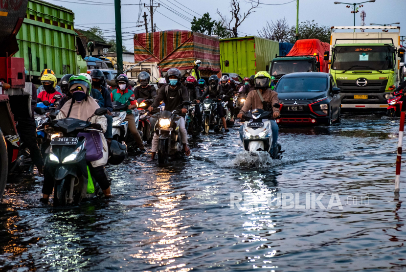 Kendaraan bermotor menembus jalan raya pantura Demak KM 8 ruas Demak-Semarang yang terendam limpasan air laut, ilustrasi
