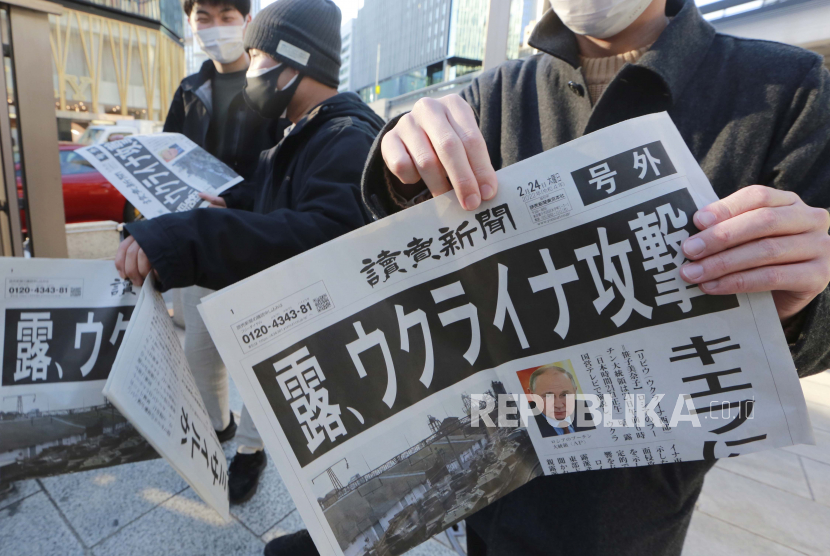 Pejalan kaki menerima salinan edisi tambahan yang melaporkan tindakan militer Rusia di Ukraina, di Tokyo, Kamis, 24 Februari 2022. 