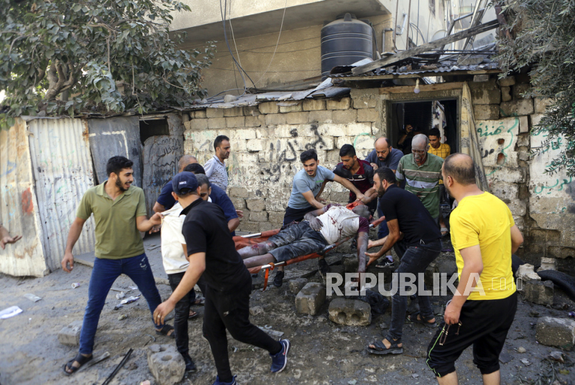 Warga Palestina membawa jenazah seorang pria pasca serangan udara Israel yang menghantam gedung-gedung, di Kota Gaza, pusat Jalur Gaza, Minggu, 15 Oktober 2023.