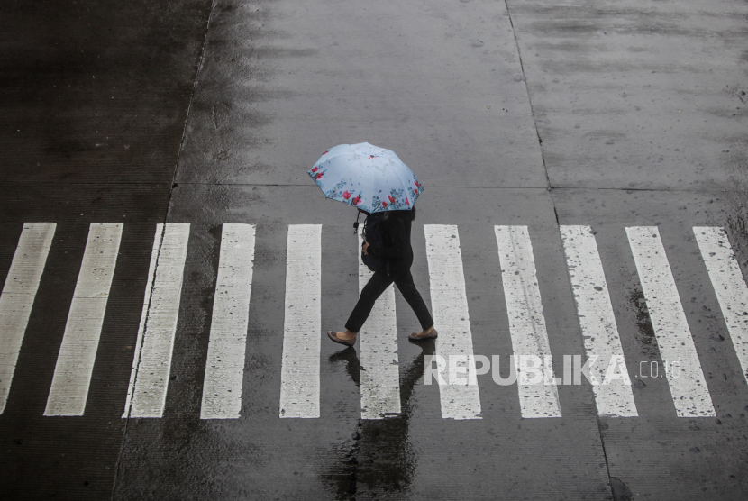 Warga memakai payung saat hujan turun di kawasan Blok M, Jakarta Selatan, (ilustrasi)