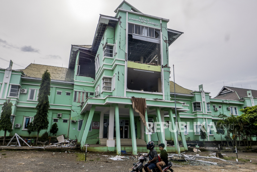 Pengendara sepeda motor melewati rumah sakit yang rusak akibat gempa berkekuatan 6,2 skala Richter di Mamuju, Sulawesi Barat, Indonesia, 17 Januari 2021. Sedikitnya 73 orang tewas dan ratusan lainnya luka-luka setelah gempa bumi 6,2 skala Richter melanda pulau Sulawesi pada 15 Januari.