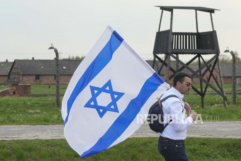 Seorang pria berjalan dengan bendera Israel (ilustrasi). 