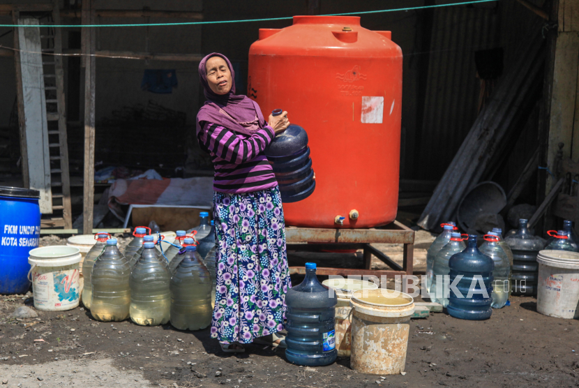 Seorang warga mengangkat galon berisi air seusai penyaluran bantuan air bersih di daerah krisis air bersih di Kelurahan Jabungan, Semarang, Jawa Tengah, Selasa (1/8/2023).