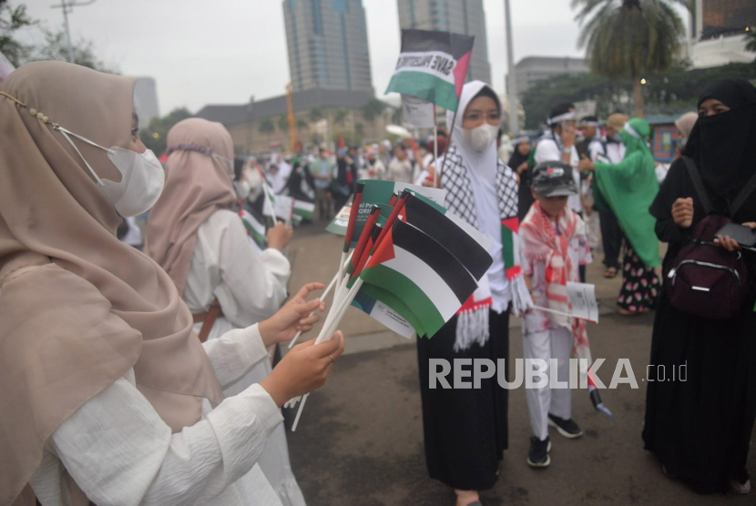 Sejumlah peserta aksi membagikan bendera palestina sebelum dimulainya Aksi DamaiAliansi Rakyat Indonesia Bela Palestina, di kawasan Monas,Ahad Jakarta (5/11/2023).