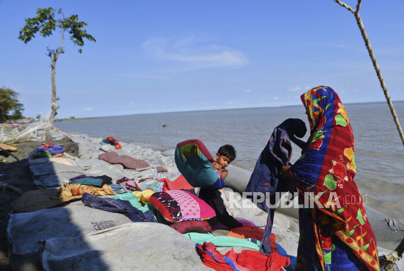 Seorang wanita Bangladesh dan seorang anak mencoba menyelamatkan barang-barang mereka setelah badai tropis Sitrang menghantam pantai Teluk Benggala di Char Fasson, distrik Bhola, Bangladesh, Selasa, 25 Oktober 2022.