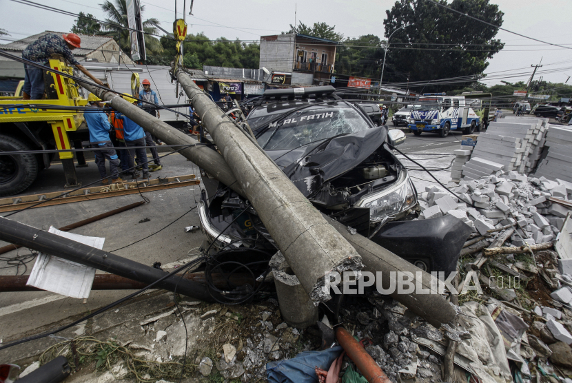 Pekerja PLN melakukan evakuasi tiang listrik yang menimpa mobil saat terjadi kecelakaan di Jalan Raya Parung, Kemang, Kabupaten Bogor, Jawa Barat, Jumat (7/7/2023). 
