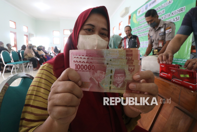 Pelaku usaha mikro memperlihatkan uang tunai saat mengambil bantuan sosial di Dinas Koperasi, Kota Kediri, Jawa Timur, Jumat (23/12/2022).