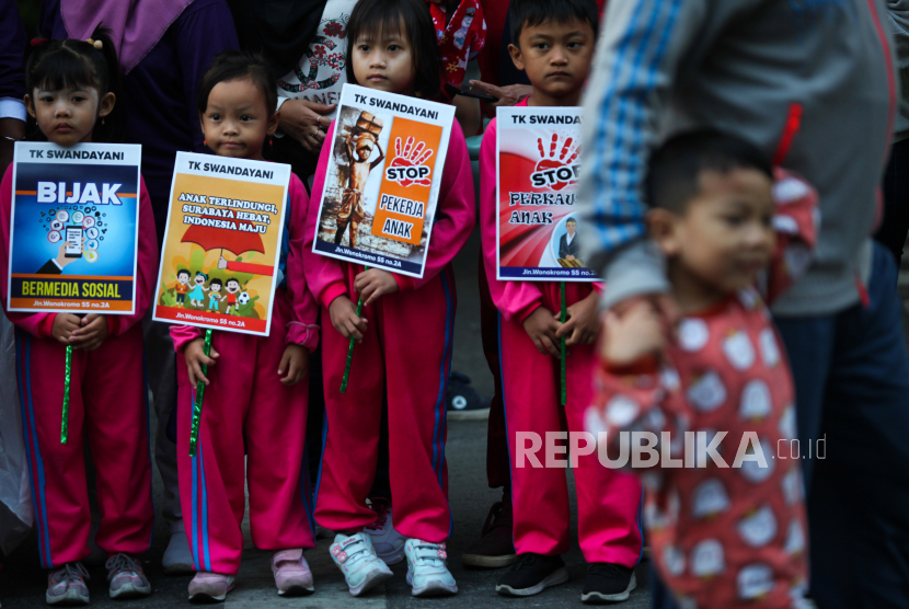 Sejumlah anak membentangkan poster saat memperingati Hari Anak Nasional pada Hari Bebas Kendaraan Bermotor atau Car Free Day di Jalan Darmo, Surabaya, Jawa Timur, Ahad (23/7/2023). 