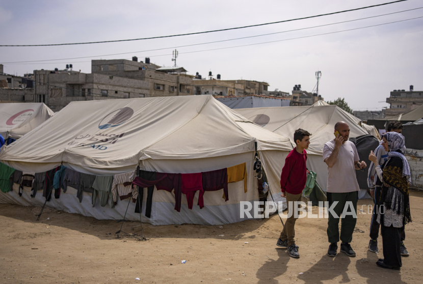 Heba al-Haddad, kanan, dan keluarganya yang mengungsi dari Kota Gaza, berdiri di kamp tenda darurat di Rafah, Gaza selatan, Jumat, (29/3/2024).