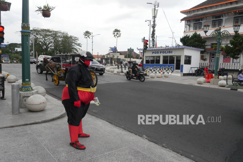 Warga dengan kostum super hero membagikan masker di titik nol Yogyakarta, Senin (17/8). Pemerintah Kota (Pemkot) Yogyakarta menerapkan sanksi bagi yang melanggar protokol pencegahan Covid-19. Sanksi ini berupa denda sebesar Rp 100 ribu.