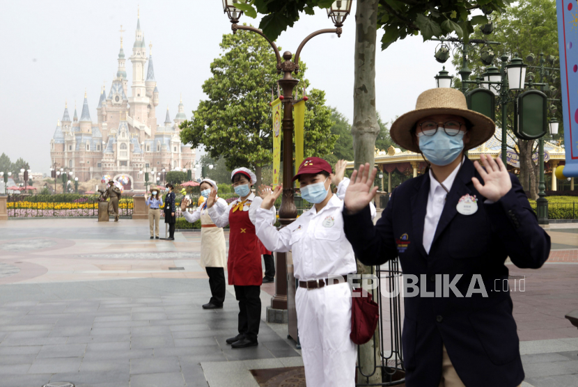 Staf taman mengenakan masker menyambut pengunjung di taman hiburan Disneyland saat dibuka kembali setelah penutupan imbas virus corona di Shanghai, China, Senin (11/5). Taman hiburan paling terkemuka di China dibuka kembali pada hari Senin untuk mampu mengontrol penyebaran virus corona dan untuk memulihkan bidang perekonomian