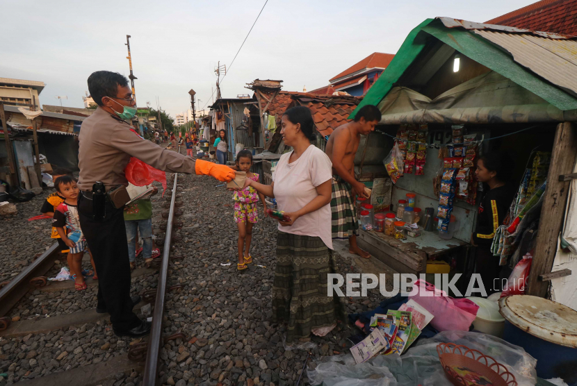 Polisi membagikan makanan berbuka puasa kepada warga di kawasan Bubutan DKA, Surabaya, Jawa Timur, Jumat (24/4). Mulai 28 April 2020 PSBB diberlakukan di Kota Surabaya.