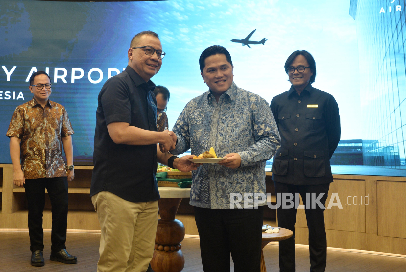 Menteri BUMN Erick Thohir (kanan) memberikan potongan tumpeng kepada Dirut InJourney Airports Faik Fahmi (tengah).