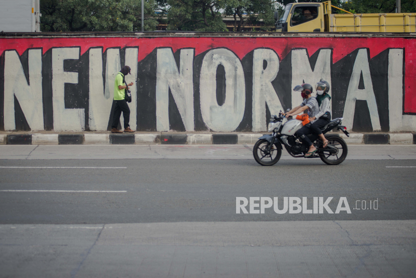 Pengendara melintasi mural new normal di Jalan T.B Simatupang, Jakarta, Sabtu (6/6)
