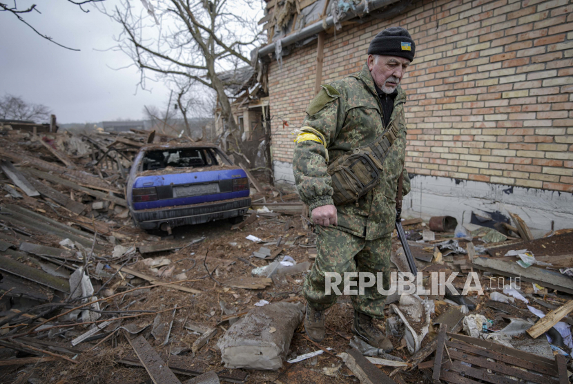 Andrey Goncharuk, 68, seorang anggota pertahanan teritorial, berjalan di halaman belakang sebuah rumah yang rusak akibat serangan udara Rusia, menurut penduduk setempat, di Gorenka, di luar ibu kota Kyiv, Ukraina, Rabu, 2 Maret 2022. 
