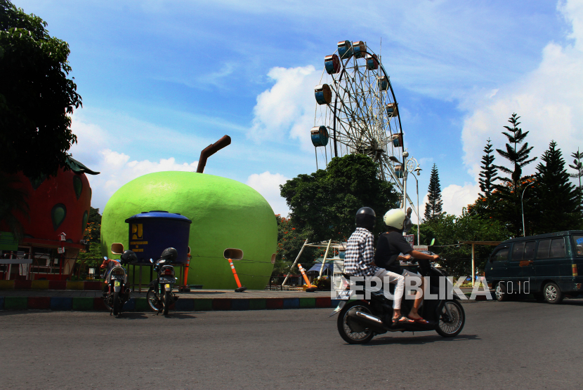 Pengendara motor melintas di depan wahana wisata bianglala yang ditutup saat penerapan Pembatasan Sosial Berskala Besar (PSBB) di Alun-alun Kota Batu, Jawa Timur. (ilustrasi)