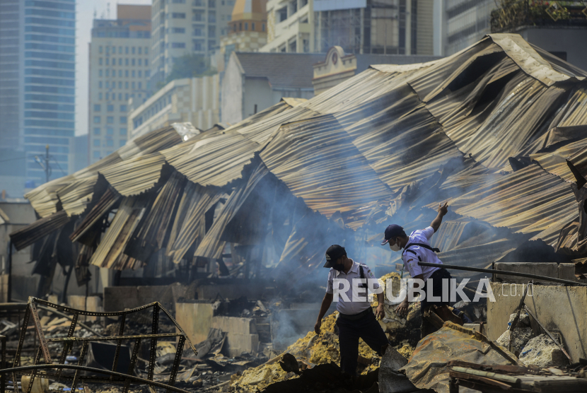 Petugas melintas di lokasi pasca kebakaran di Pasar Kambing, Tanah Abang, Jakarta, Jumat (9/4). 