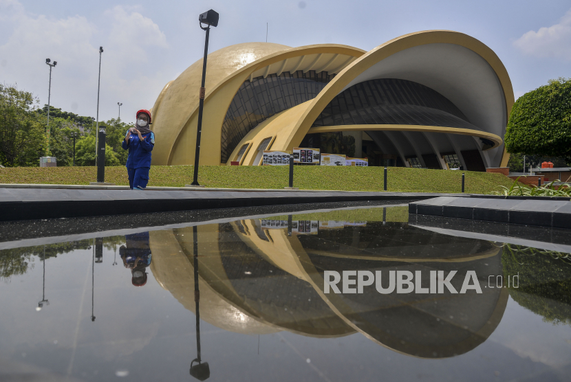Pekerja berjalan dengan latar belakang Teater Keong Emas di Taman Mini Indonesia Indah (TMII), Jakarta, Rabu (28/9/2022). Proses revitalisasi TMII telah mencapai 98 persen dan direncanakan akan menjadi salah satu lokasi KTT G20. 