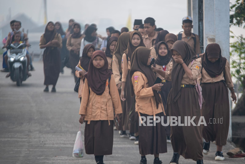 Sejumlah pelajar berjalan menuju sekolah di tengah kabut asap (ilustrasi).