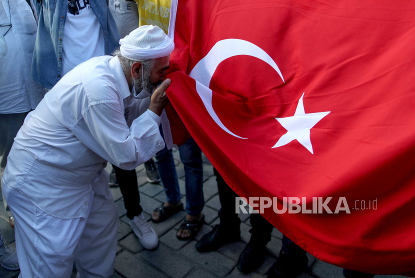 Perjalanan Hagia Sophia . Foto: Seorang pria mencium bendera nasional Turki di depan Museum Hagia Sophia, di Istanbul, Turki, 10 Juli 2020. Pengadilan administrasi tertinggi Turki pada 10 Juli 2020 memutuskan bahwa museum yang dulunya adalah masjid yang dibangun di Katedral dapat diubah menjadi sebuah masjid lagi dengan menetapkan statusnya sebagai museum.