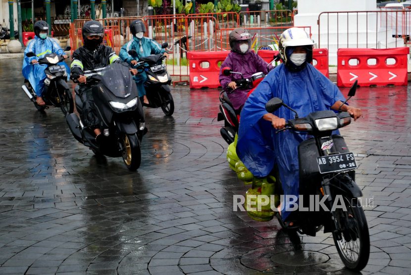 Pengendara menggunakan jas hujan saat melintas di kawasan Tugu, Yogyakarta.