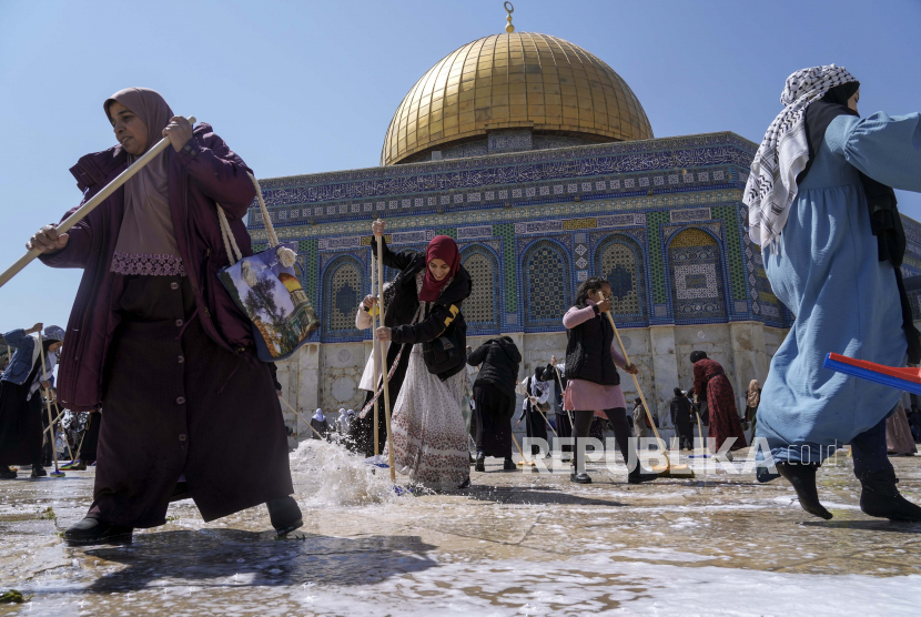 Relawan Palestina membersihkan kompleks Masjid Al-Aqsha, di depan Masjid Kubah Batu, menjelang bulan suci Ramadhan, di Kota Tua Yerusalem, Sabtu, 26 Maret 2022.