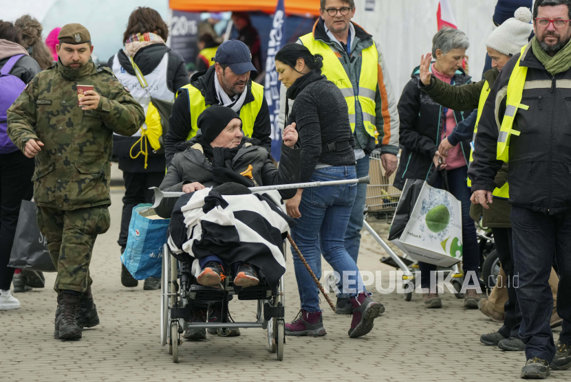 Relawan membantu seorang pengungsi di kursi roda setelah melarikan diri dari perang dari negara tetangga Ukraina, di perbatasan di Medyka, Polandia tenggara, Rabu, 6 April 2022.