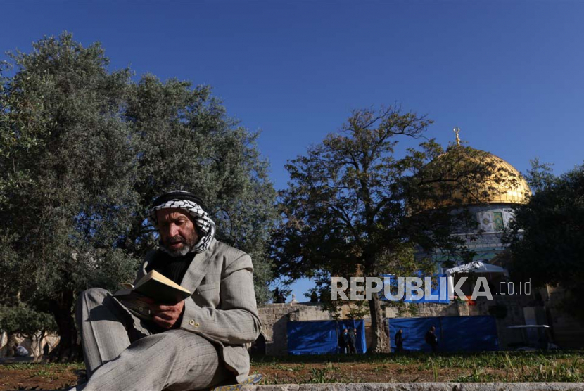 Seorang pria membaca Alquran di luar Masjid Al-Aqsa (ilustrasi). Yerusalem Palestina memiliki kedudukan yang agung di sisi Islam