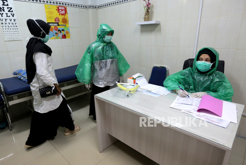 Petugas medis Puskesmas Ulee Kareng memakai jas hujan plastik sebagai alat pelindung diri (APD) saat melayani pasien. Jumlah kasus positif corona di Kota Bandung hingga Ahad (12/4) mencapai 77 orang. Ilustrasi.