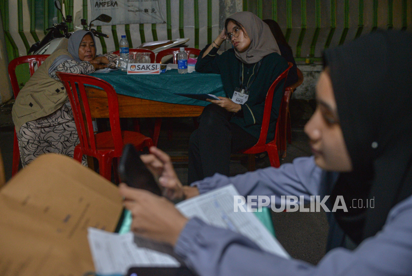 Anggota KPPS melakukan rekap penghitungan surat suara yang berlangsung hingga malam hari  di Tempat Pemungutan Suara (TPS) 