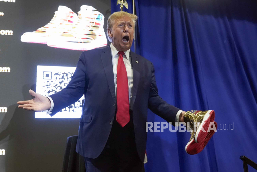 Donald Trump memegang sepatu kets emas Trump di Sneaker Con Philadelphia, Sabtu, (17/2/2024).