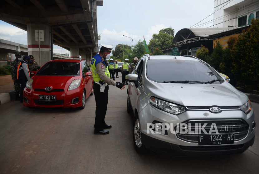 Petugas melakukan pengecekan kepada pengendara dengan plat nomor luar daerah yang melintasi Check Point PSBB di kawasan Kalimalang, Jakarta, Selasa (26/5). Pemerintah Provinsi DKI Jakarta menerapkan aturan penggunaan Surat Izin Keluar-Masuk (SIKM) untuk membatasi warga yang keluar masuk Jakarta pada masa arus balik