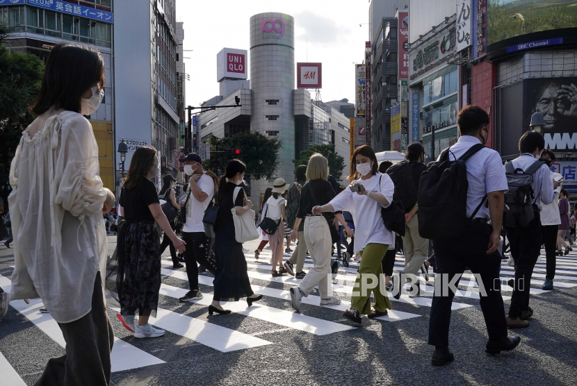 Orang-orang muda yang mengenakan masker pelindung berjalan di persimpangan jalan di Shibuya, dekat department store mode Shibuya 109, di Tokyo, Jepang, 03 Agustus 2020. 