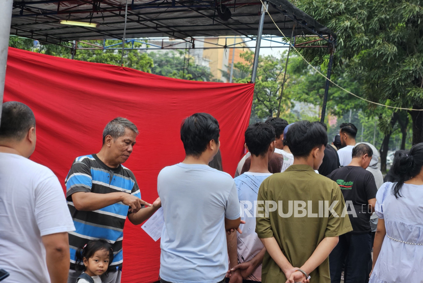 Antrean warga yang hendak mencoblos di TPS 24 Cempaka Baru, Kemayoran, Jakarta Pusat, Rabu (14/2/2023). Tenda TPS ini sempat ambruk pada dini hari tadi akibat hujan deras.