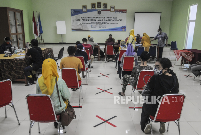 Petugas melayani orang tua siswa di posko Penerimaan Peserta Didik Baru (PPDB) di SMA Negeri 70, Jakarta.